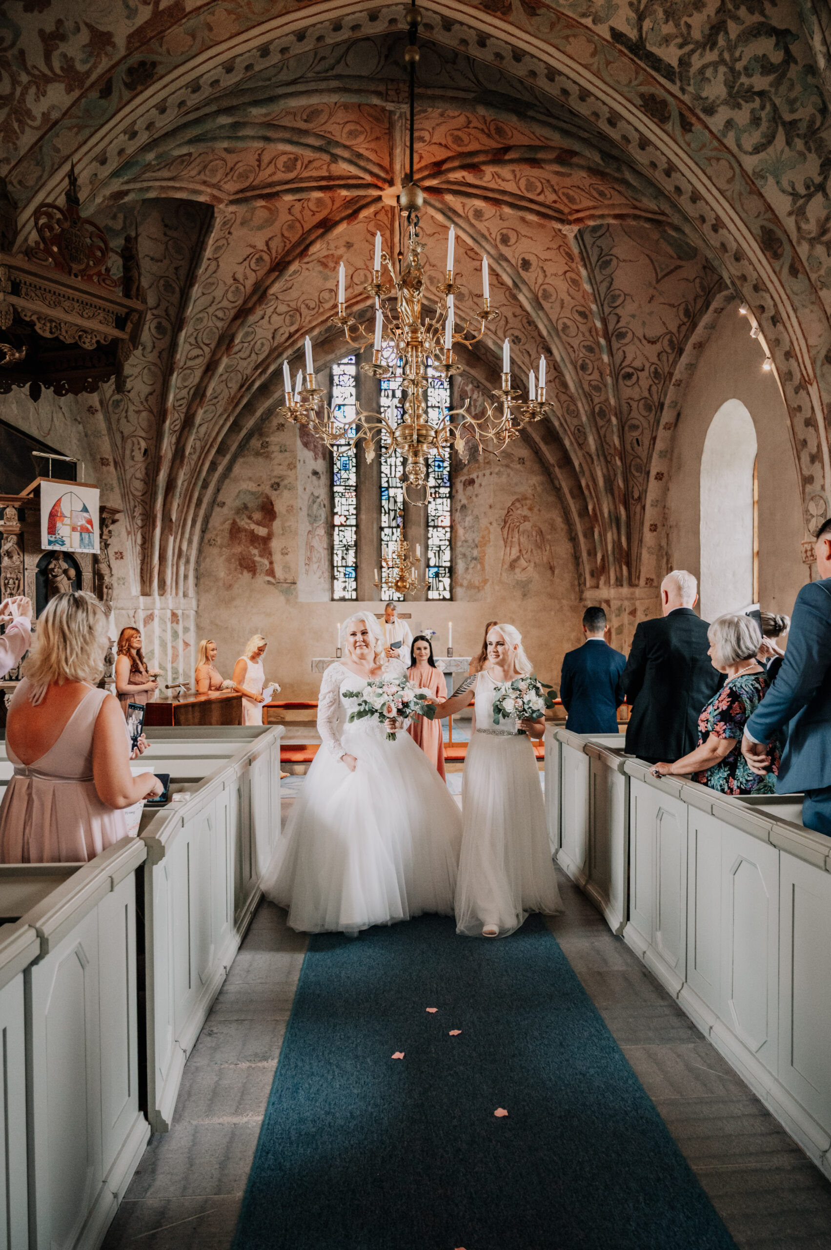 Vigseln, brudparet två tjejer som gift sig kommer gående i altargången i Björksta kyrka utanför Västerås. Foto Martina Ardbäck