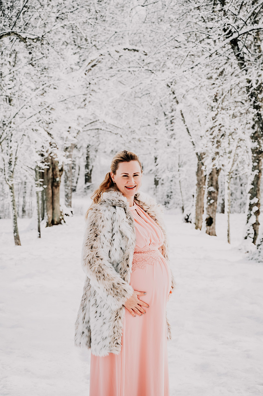 Gravidfotografering på vintern i en allé i ett vit vinterlandskap. Rosa gravidklänning. Fotat i Strängnäs kommun. Gravidfotograf Martina Ardbäck